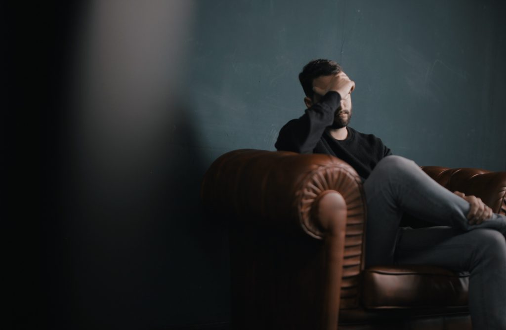 Man holding his head sitting on sofa